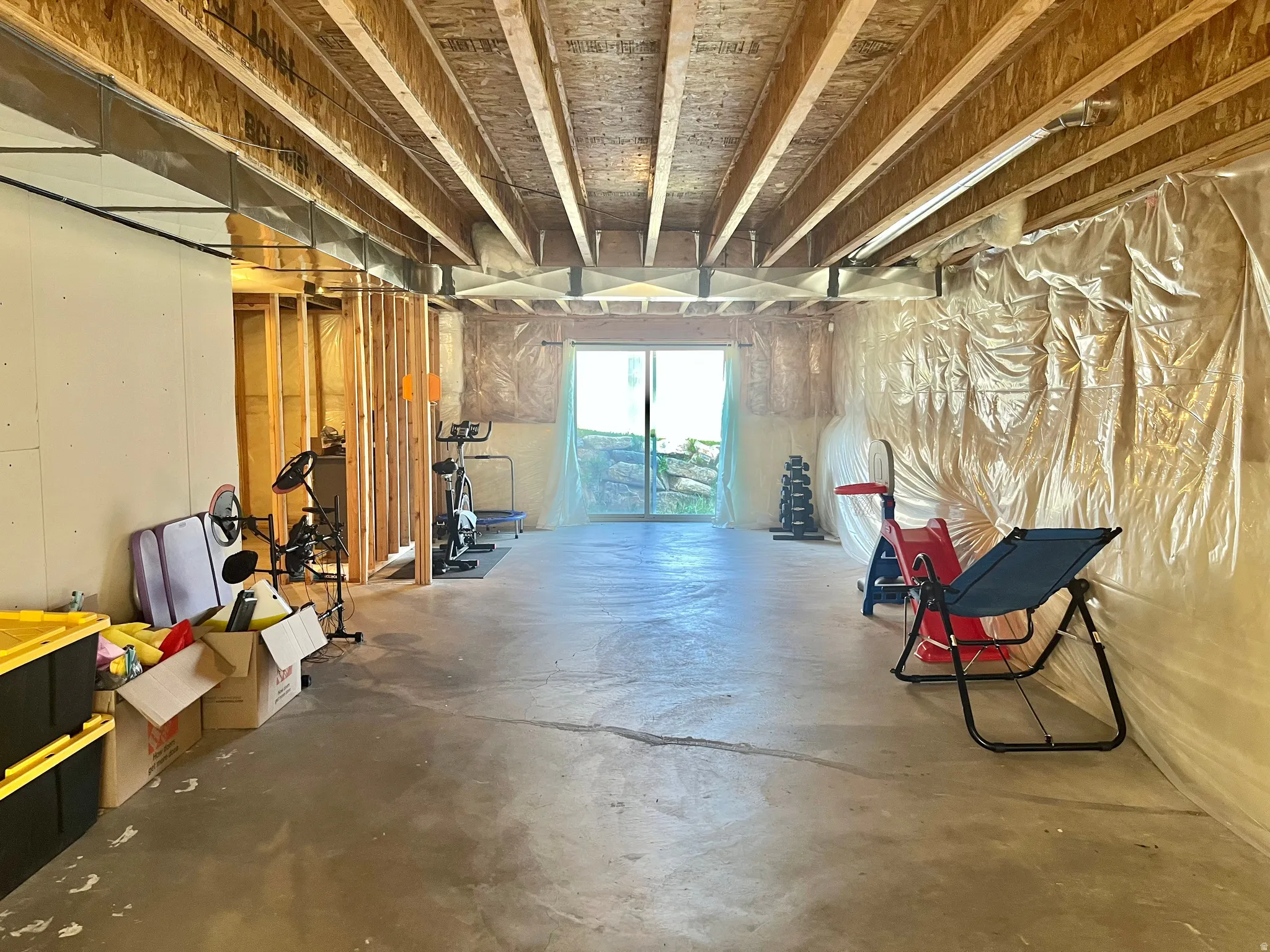 Unfinished basement with exposed ceiling joists and concrete flooring