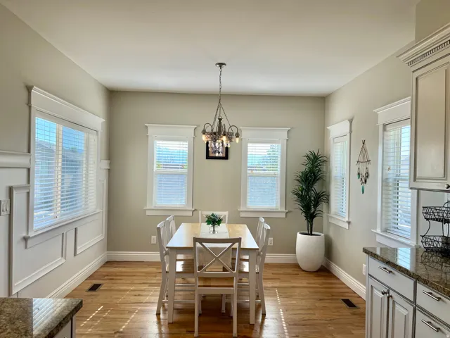 Dining area featuring wood-finish flooring, white window blinds, and an ornate chandelier