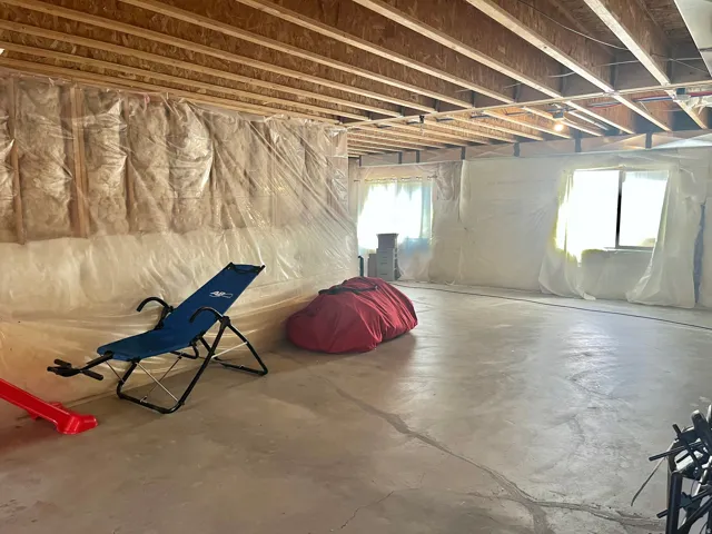 Unfinished basement with exposed ceiling joists, concrete flooring, and insulated walls