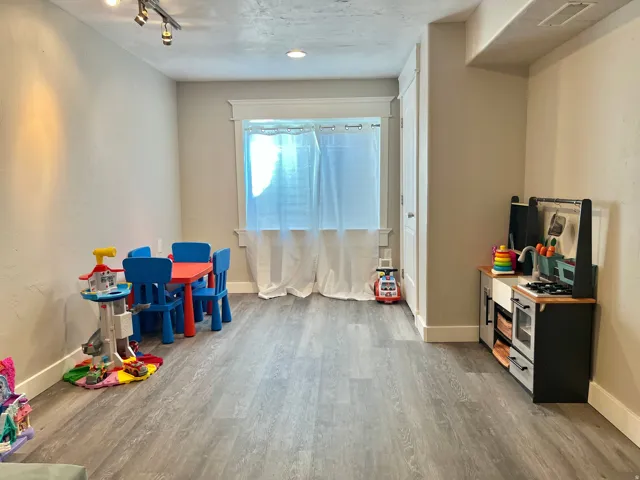 Spacious room featuring wood-finish flooring, recessed lighting, and a window with white trim
