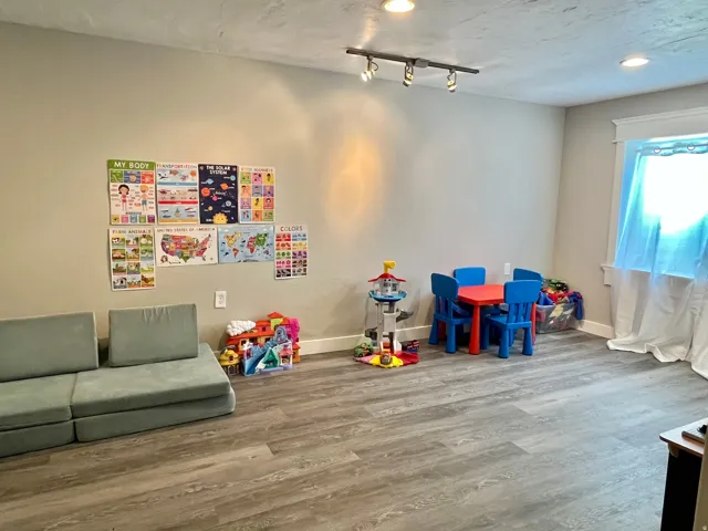 Spacious room featuring wood-finish flooring, recessed lighting, and track lighting