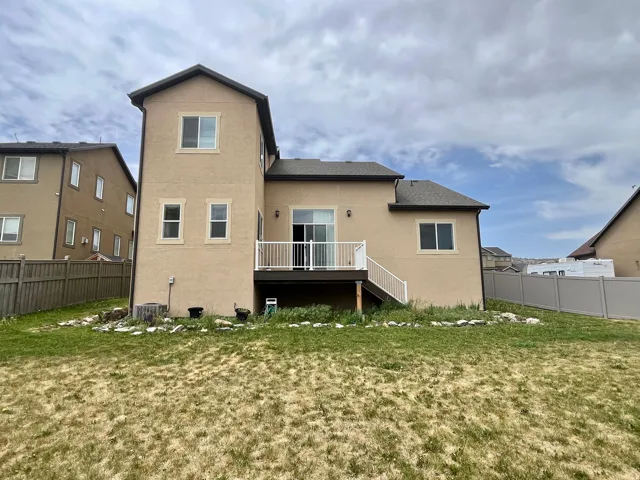 Two-story stucco exterior featuring a rear deck with white railings and a sliding glass door