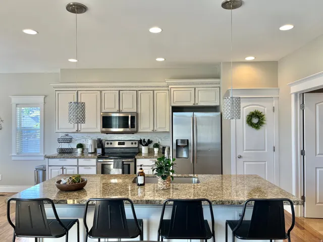 Open-concept kitchen featuring an expansive granite countertop island with seating