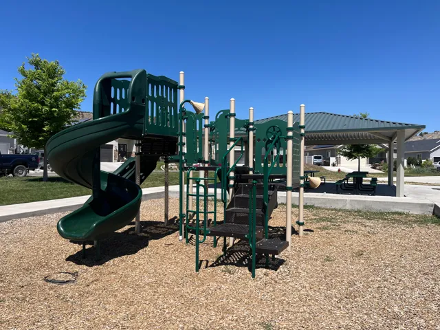 On-site playground featuring a spiral slide, climbing elements, and a protective wood chip surface