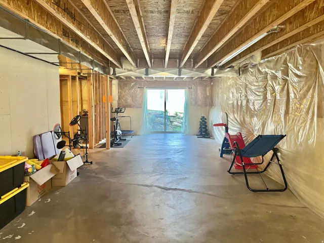 Unfinished basement with exposed ceiling joists and concrete flooring