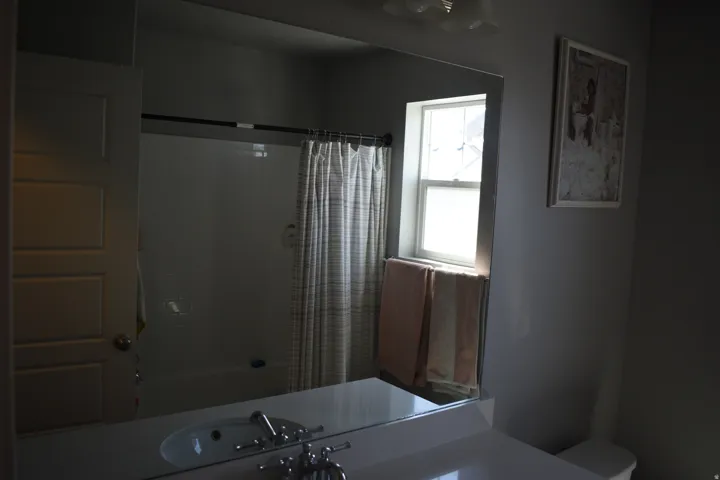 Bathroom featuring a white vanity with an integrated sink, polished chrome faucet, and a large mirror