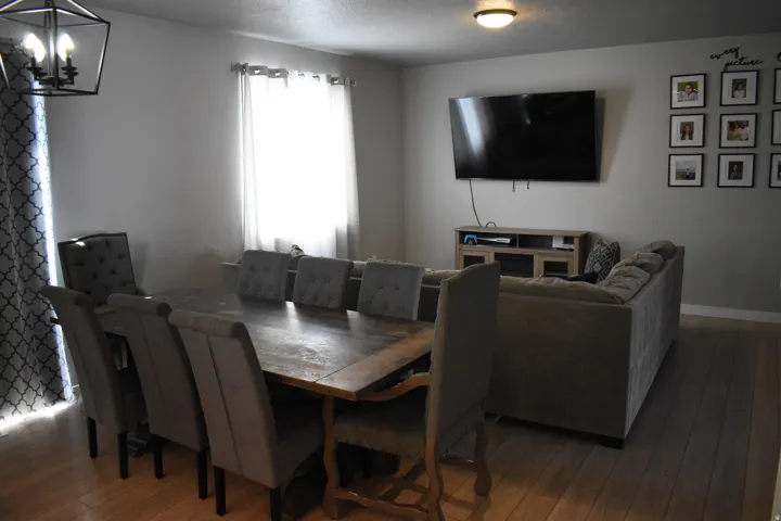 Open-concept living area featuring wood-finish flooring, recessed lighting, and a window with light-filtering curtains