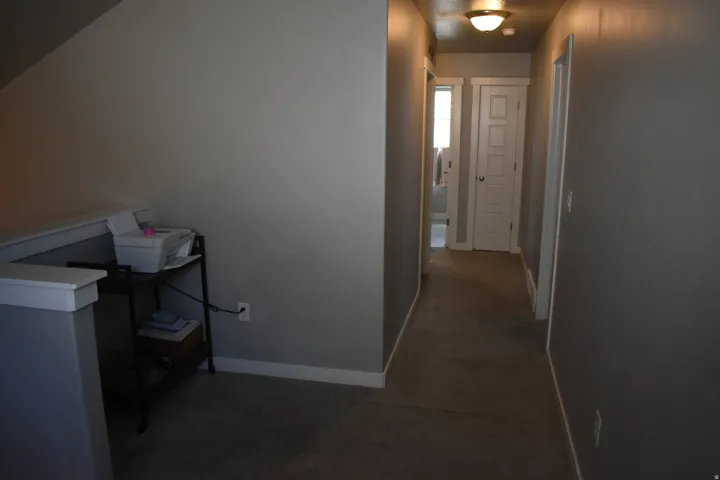 Carpeted hallway with painted walls, white trim, and a flush mount ceiling light fixture