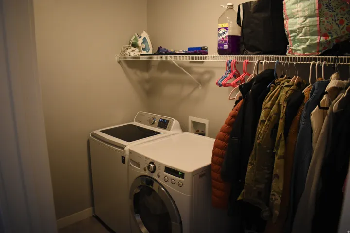 Dedicated laundry area featuring a white wire shelving unit with integrated hanging rod, light gray walls, and white baseboards