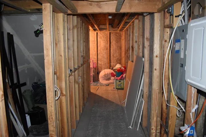 Unfinished basement area featuring exposed wood framing, electrical panel, and visible ductwork