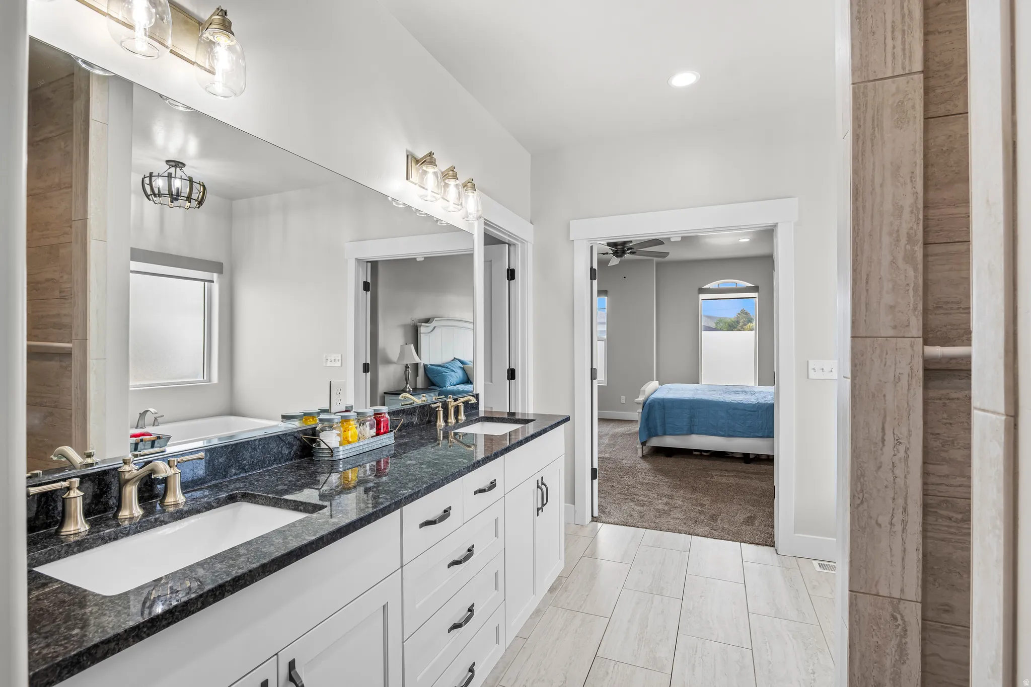 Dual vanity with dark stone countertops, undermount sinks, and brushed gold fixtures