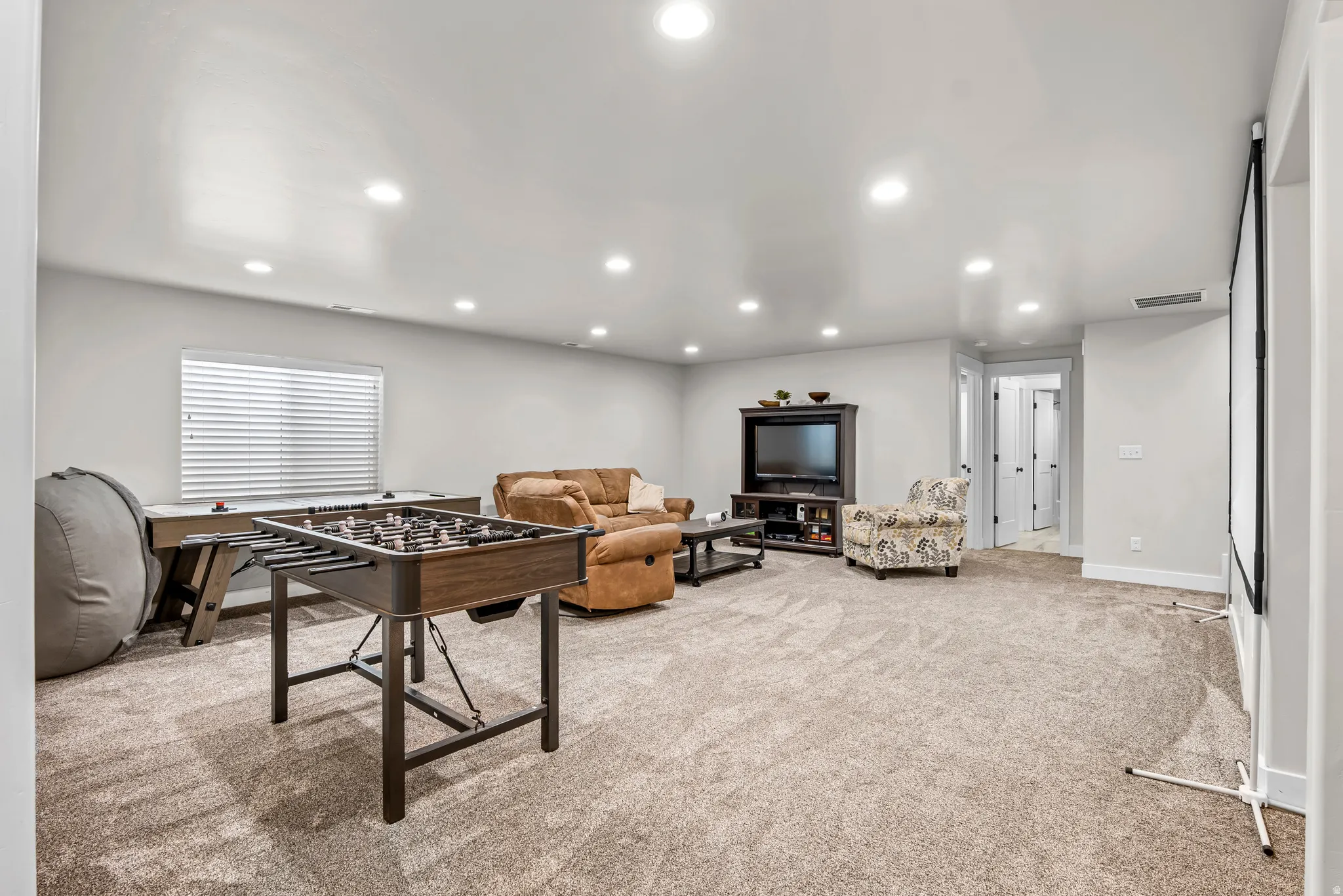 Spacious recreation room featuring recessed lighting, light gray wall paint, and plush carpeting