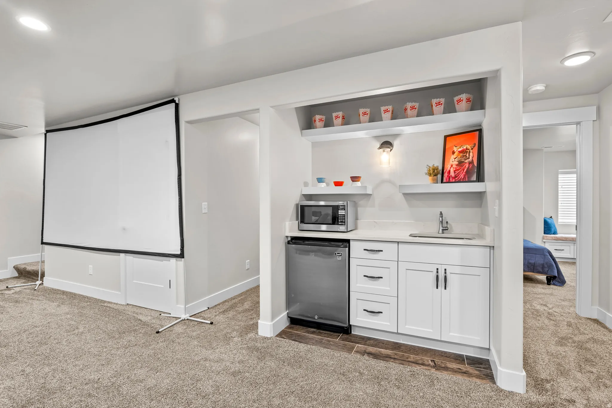 Integrated wet bar with white cabinetry, sink, and floating shelves