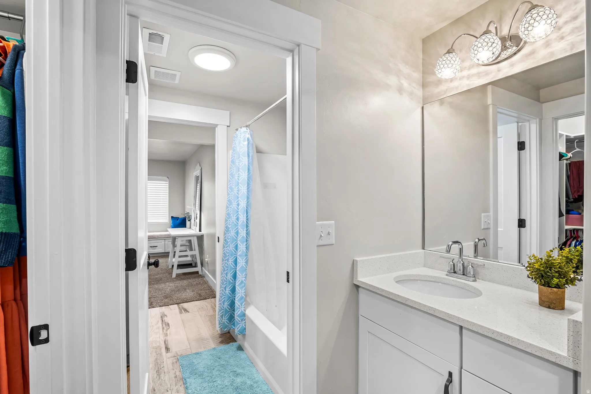 Bathroom vanity featuring a polished chrome faucet, under-mount sink, and engineered stone countertop