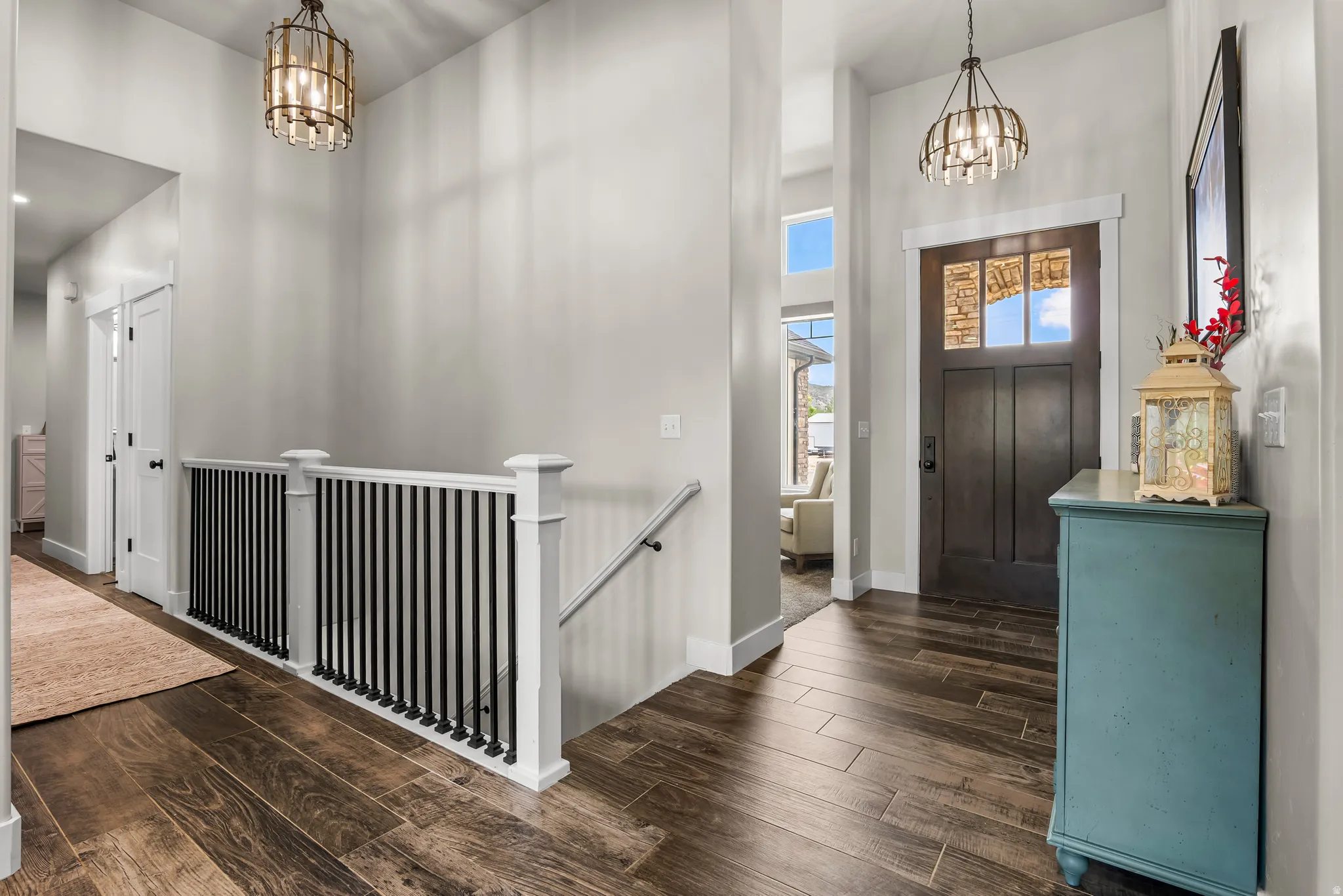Entryway featuring wood-finish flooring, a dark wood door with glass inserts, and a modern stair railing with black balusters
