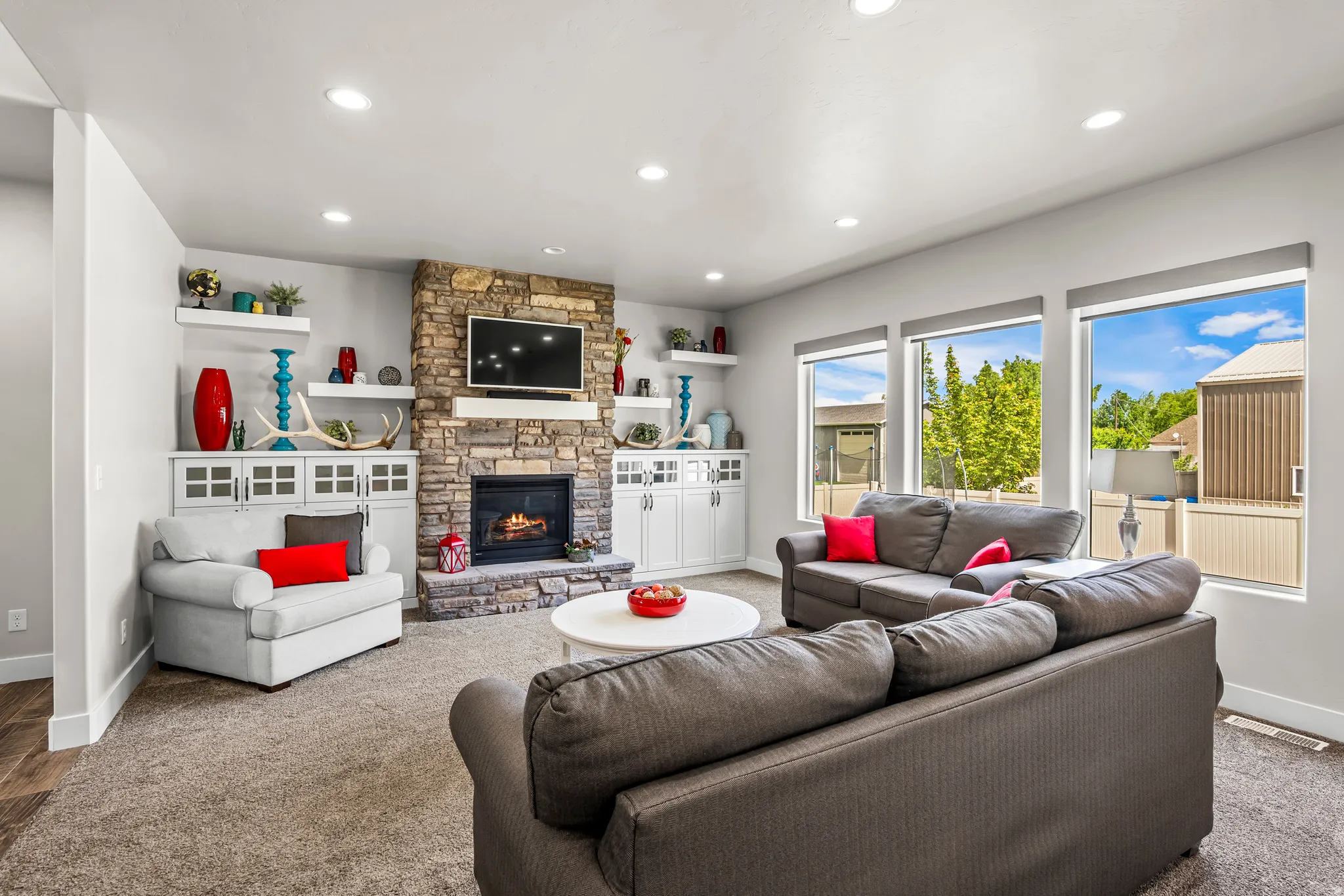 Living area featuring a floor-to-ceiling stone fireplace, recessed lighting, and large windows