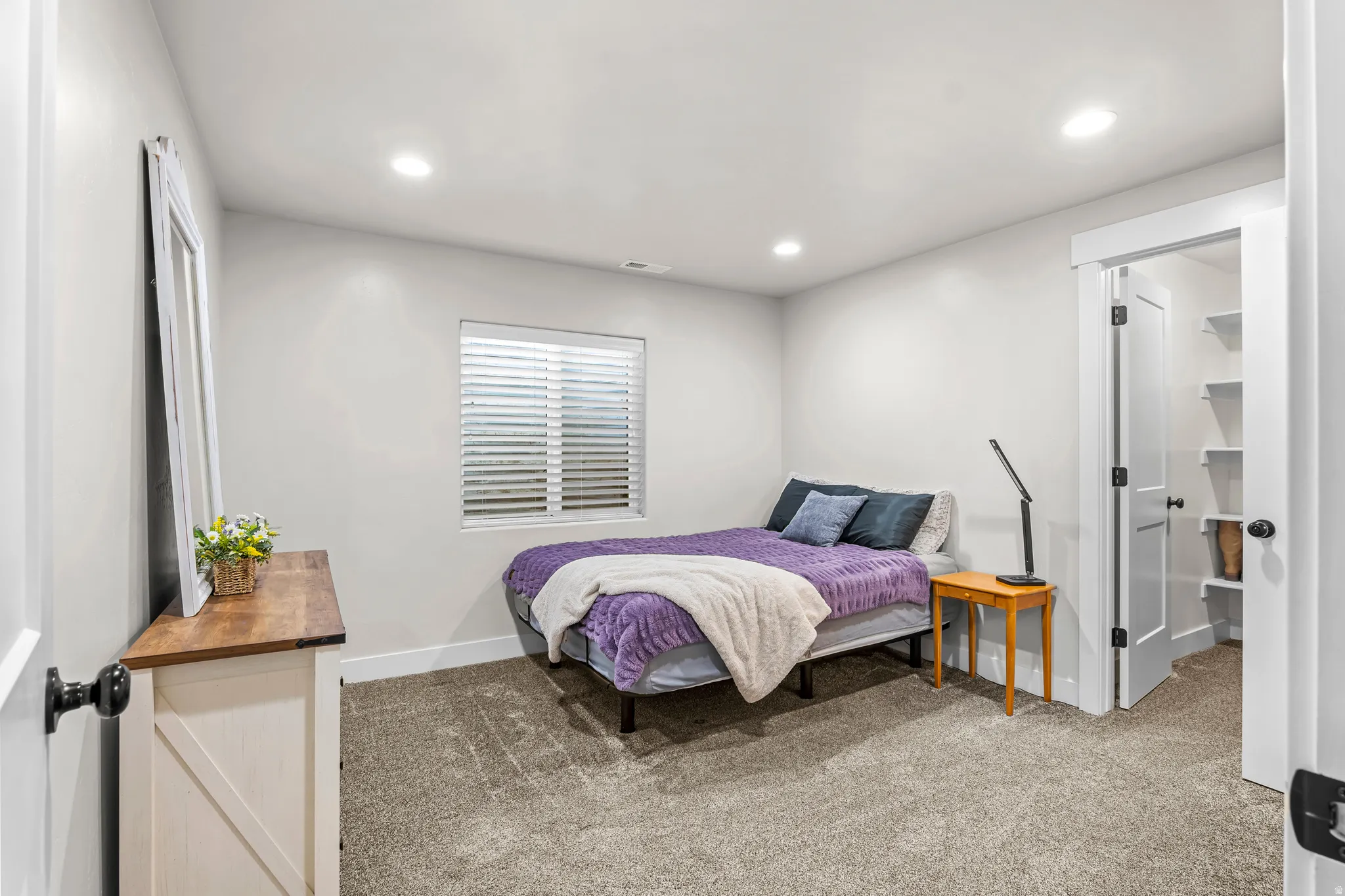Carpeted bedroom featuring recessed lighting, a window with horizontal blinds, and a built-in closet with shelving