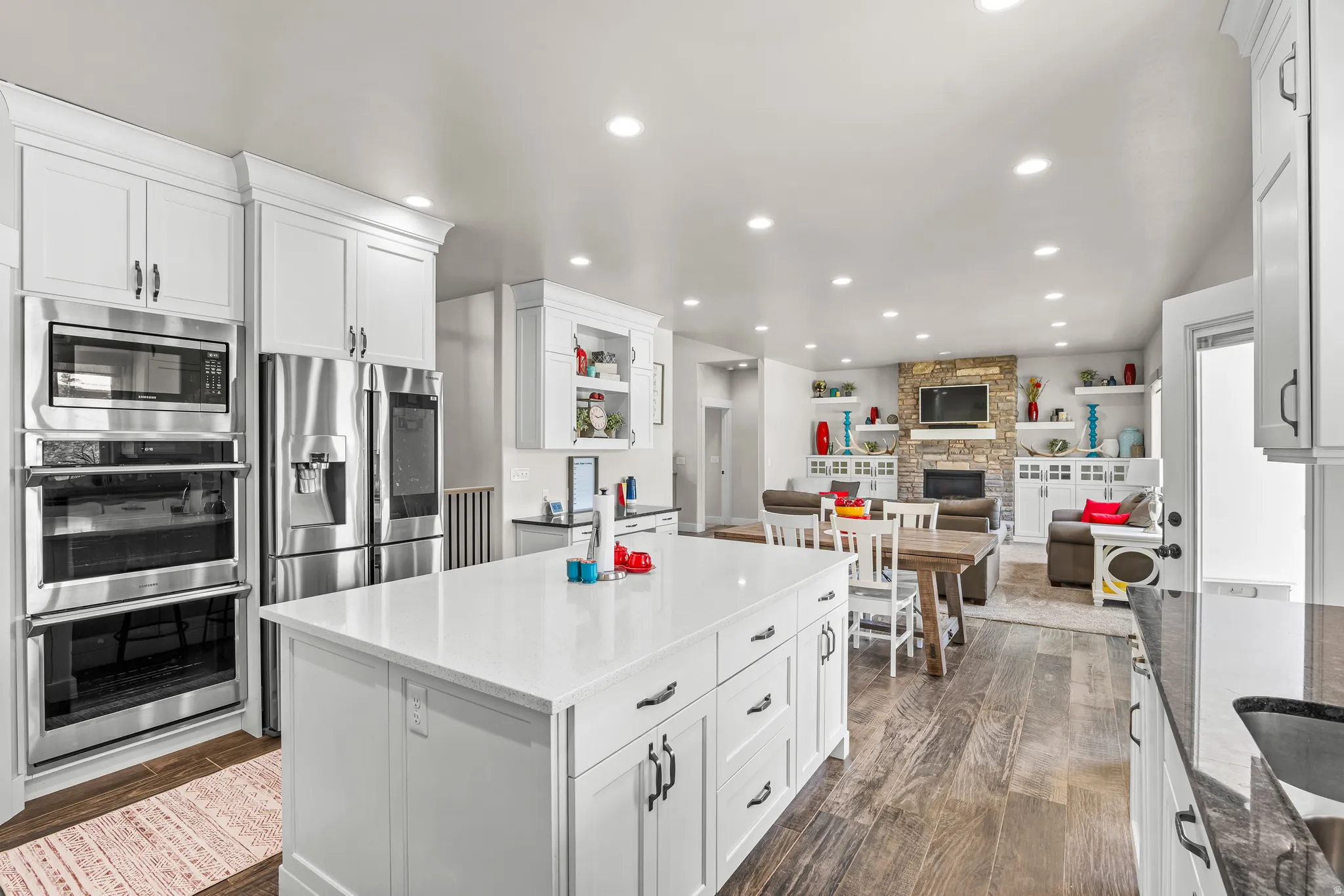 Spacious kitchen featuring an expansive central island with storage, white cabinetry, stainless steel double ovens, and a built-in microwave