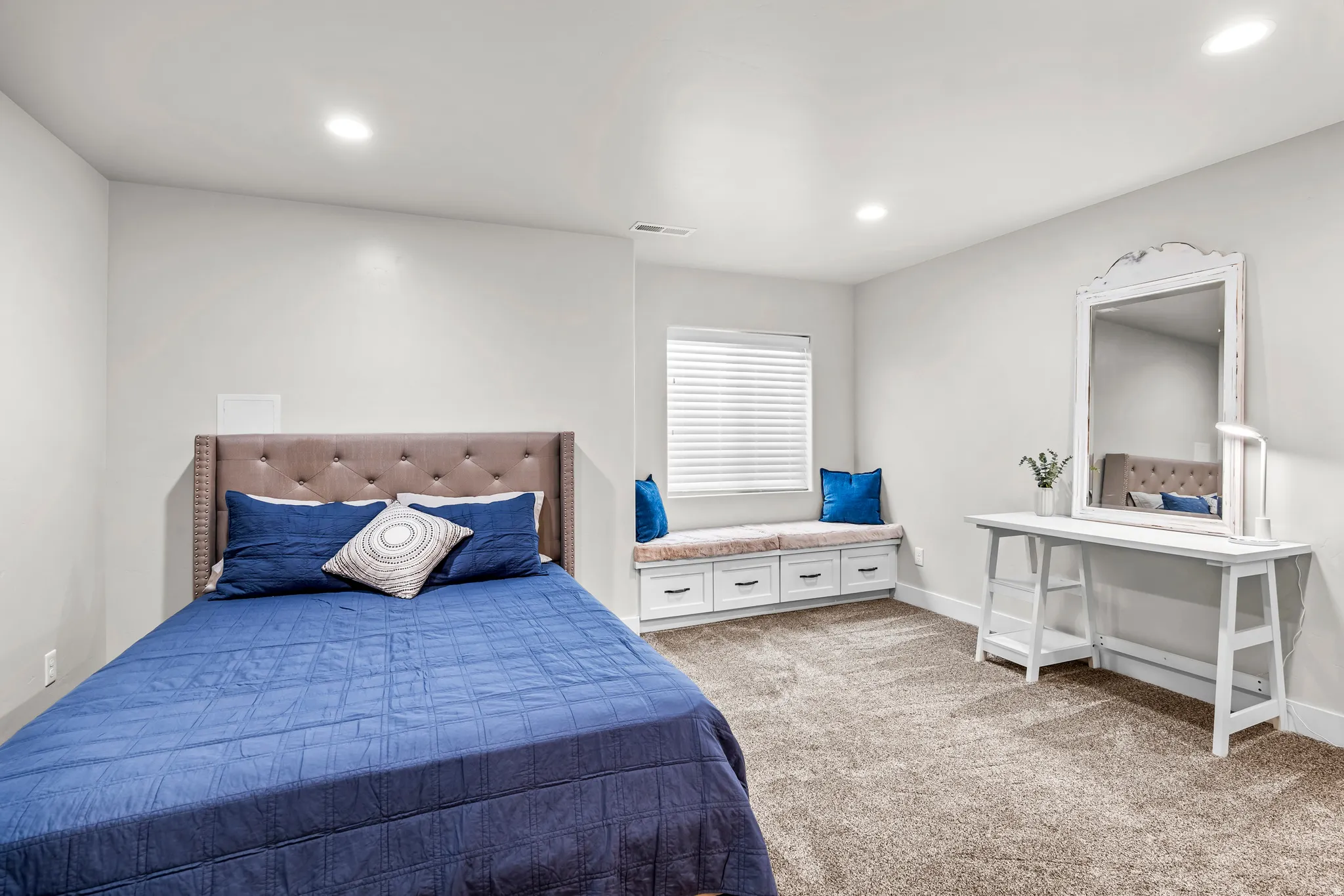 Recessed lighting illuminates this room featuring light-toned walls and plush carpeting