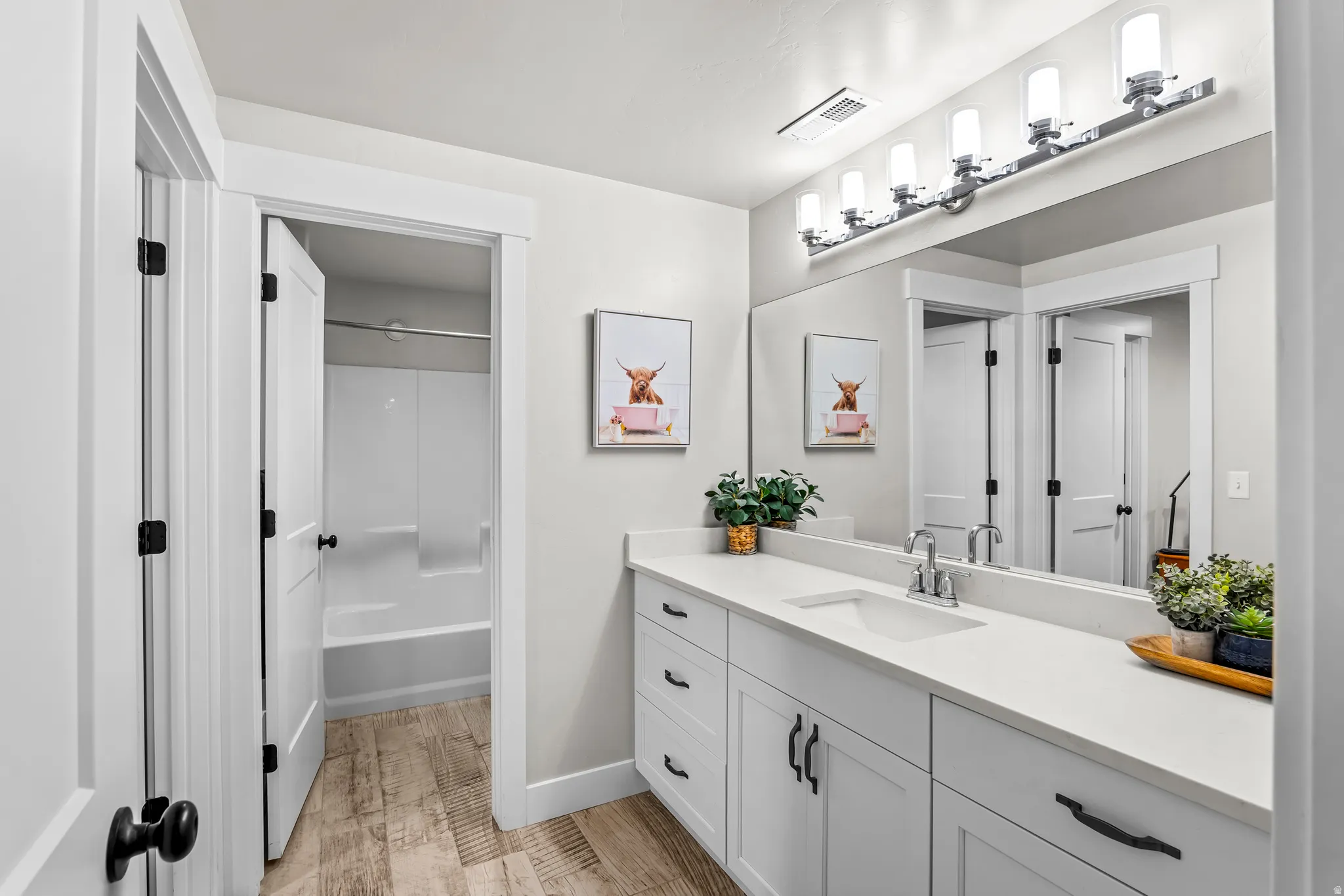 Bathroom featuring a white vanity with extensive counter space, an integrated sink, and matte black hardware