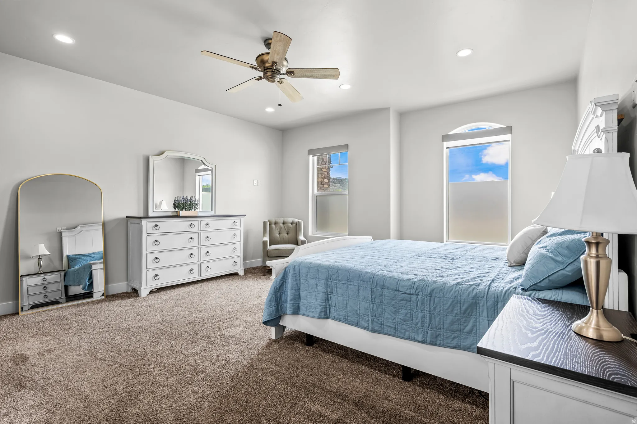 Plush carpeting provides comfort in this room featuring recessed lighting and a ceiling fan