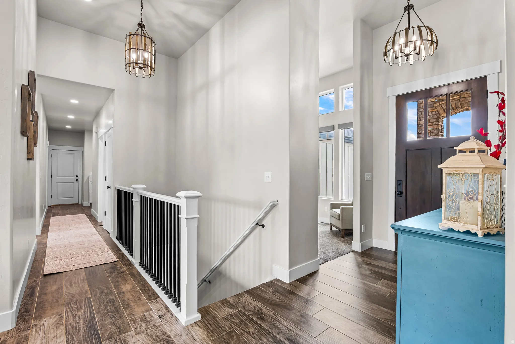 Entryway featuring wood-finish flooring, a dark wood front door with glass inserts, transom windows, and a black and white staircase railing