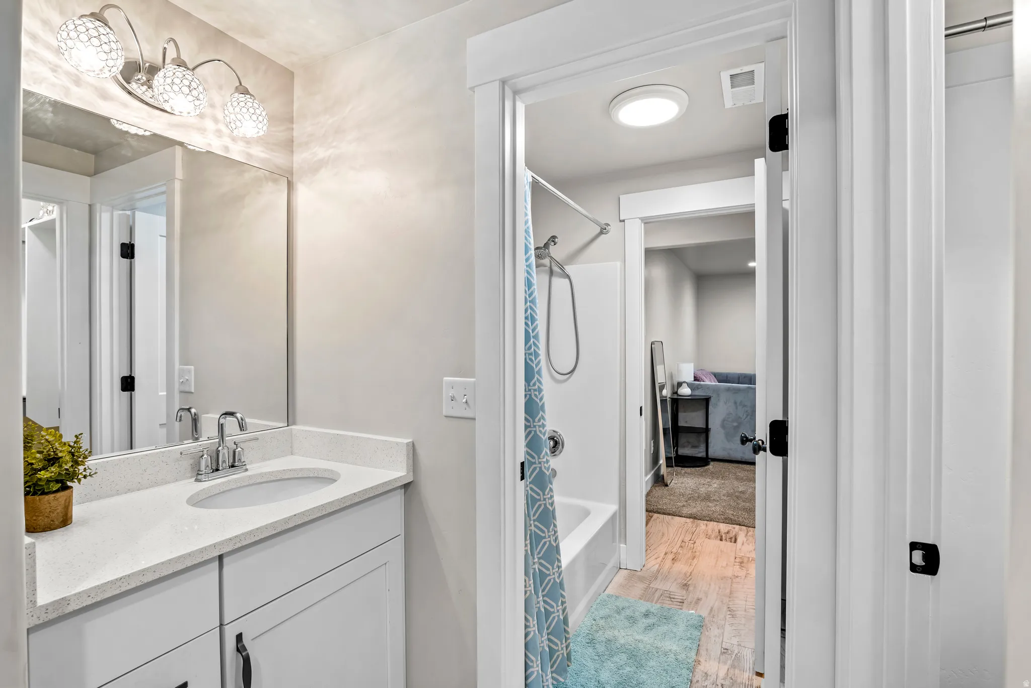 Bathroom vanity featuring a polished chrome faucet, under-mount sink, and quartz countertop