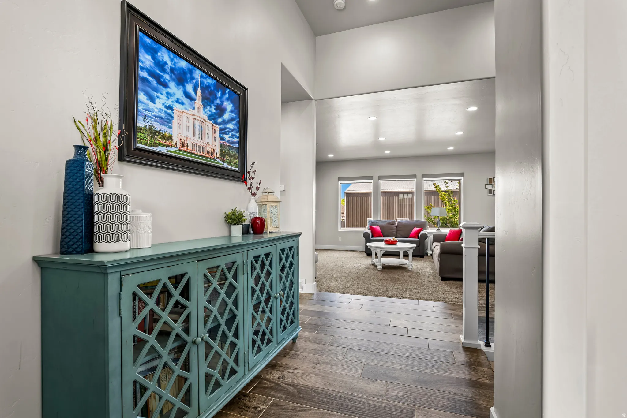 Foyer entry with wood-finish flooring, leading to a living area with recessed lighting and a window wall
