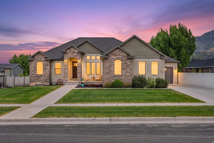 Stone and stucco exterior featuring a covered front porch, an attached garage, and a concrete driveway