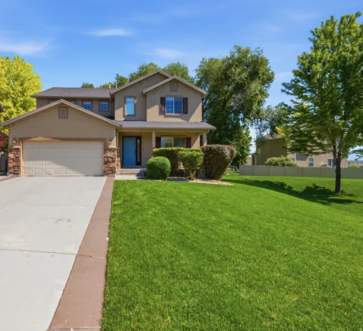 Two-story residence featuring a stucco exterior with stone accents, an attached garage, and a covered front porch with a light blue entry door