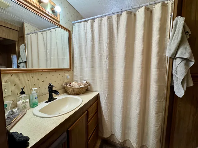 Bathroom vanity featuring an oval undermount sink, a matte black faucet, and a large framed mirror