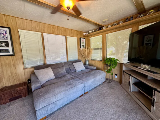 Living area featuring wood-panel walls and a light-colored ceiling with exposed wood beams