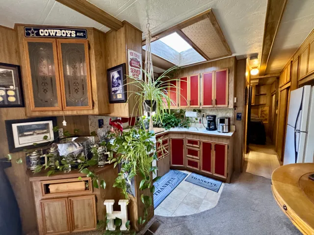 Kitchen featuring red-paneled cabinetry, a skylight, wood-look wall paneling, and ceramic tile flooring