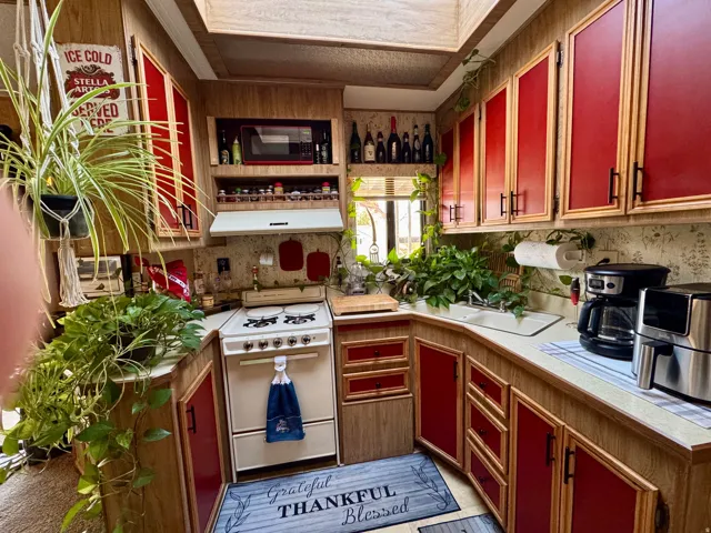 Kitchen featuring red panel cabinetry with wood-finish framing, light-toned countertops, and a white gas range with a matching range hood
