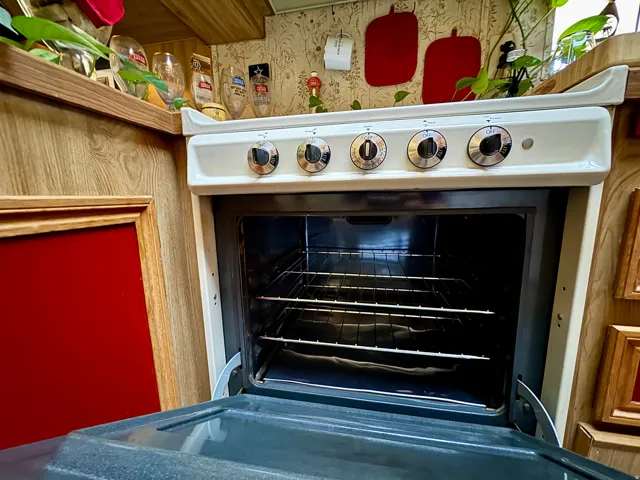 White oven with four burner controls and a visible interior rack