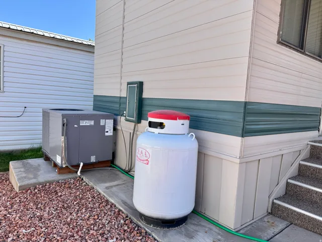 Exterior siding with a dual-tone finish, featuring a prominent air conditioning unit and a substantial propane tank