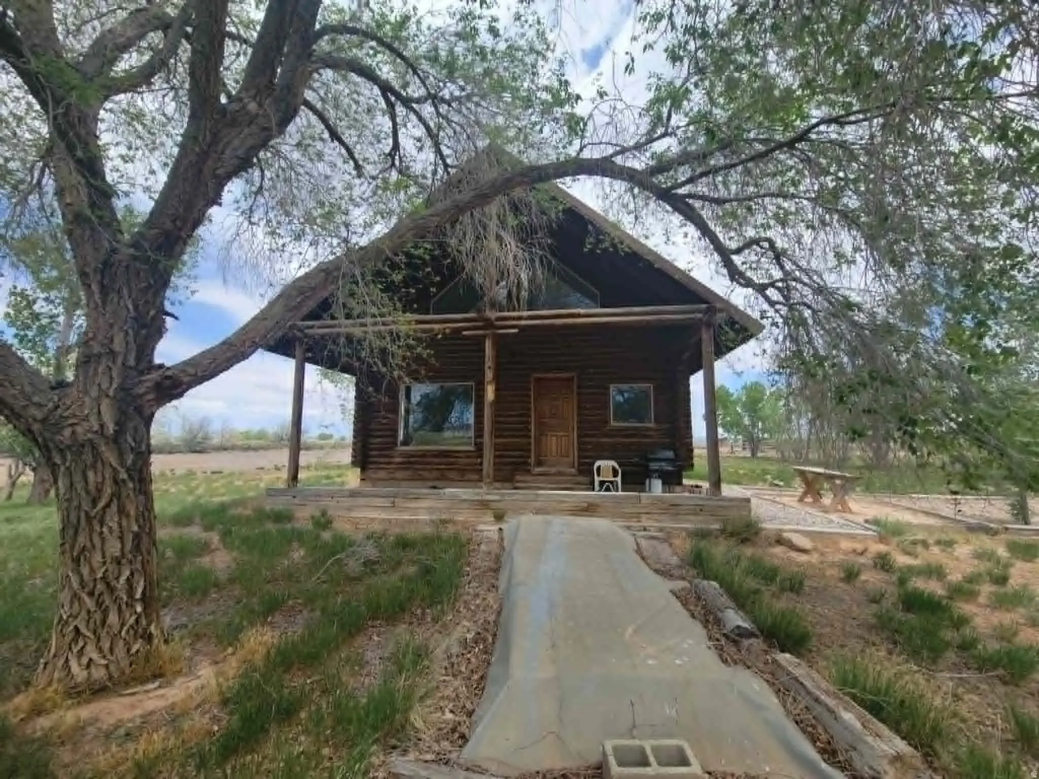 Rustic log cabin featuring a covered porch, A-frame roofline, and natural wood construction