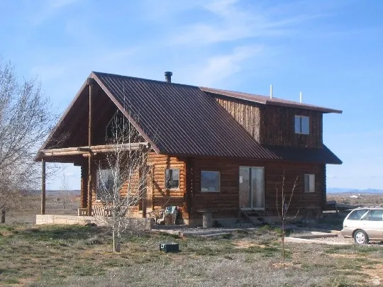 Log cabin style home featuring a brown metal roof