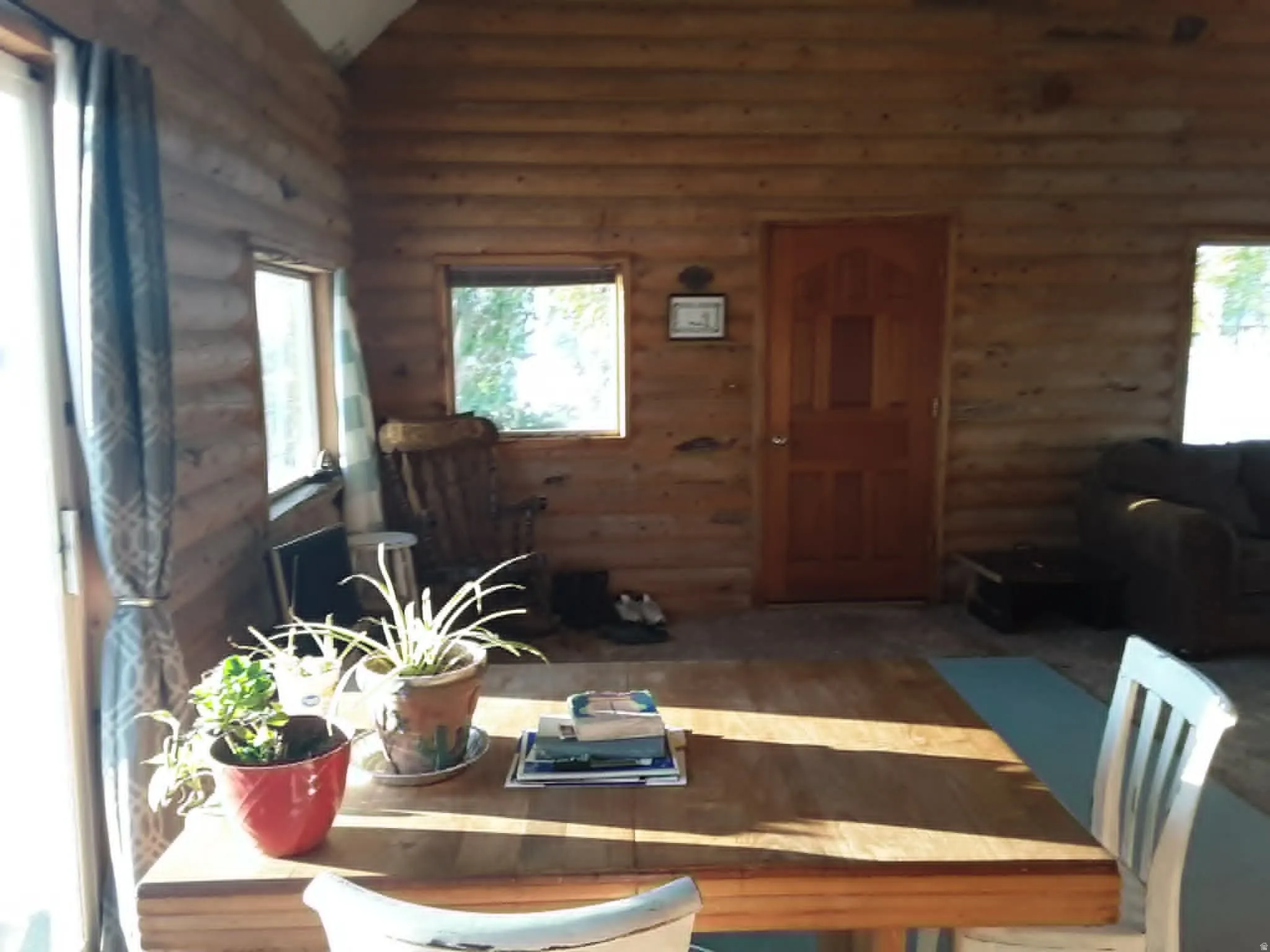 Rustic interior featuring log wall construction, natural wood door, wood-finish flooring, and multiple windows