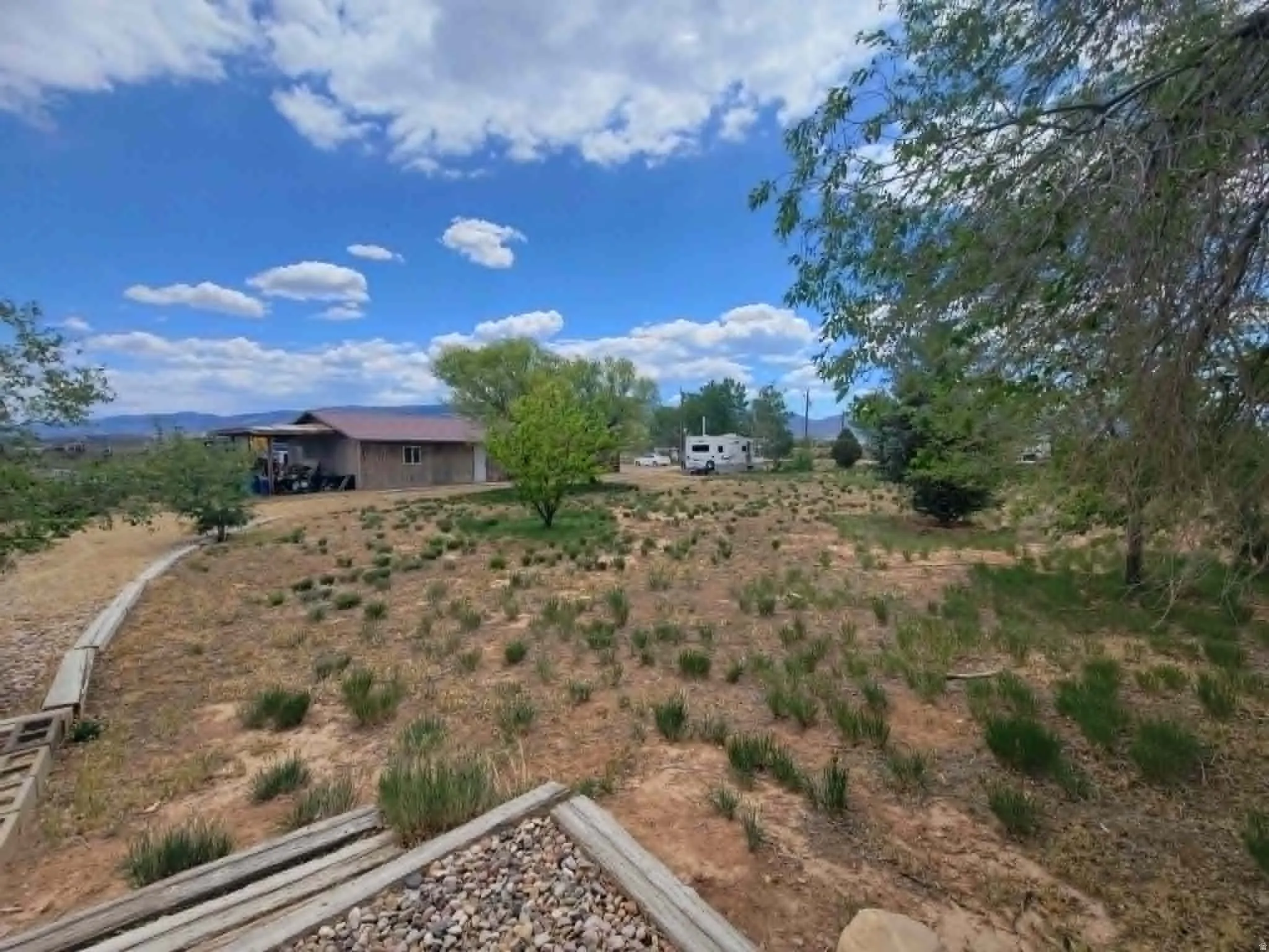 Expansive land parcel featuring a single-story residence with a covered porch and a brown roof