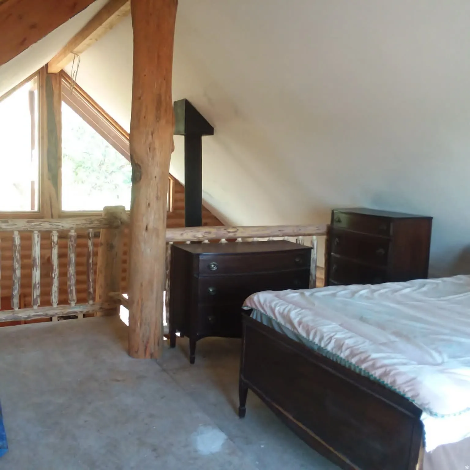 Loft space featuring a natural wood support pillar, exposed wood ceiling beams, and a wood railing