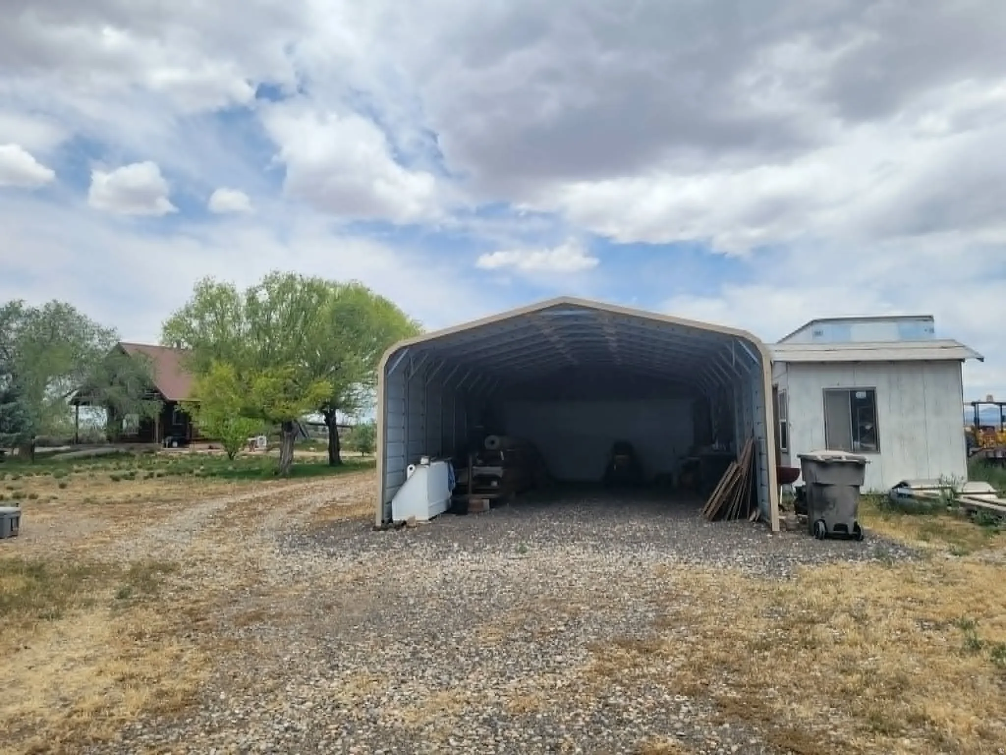 Open-sided metal carport with a gravel base