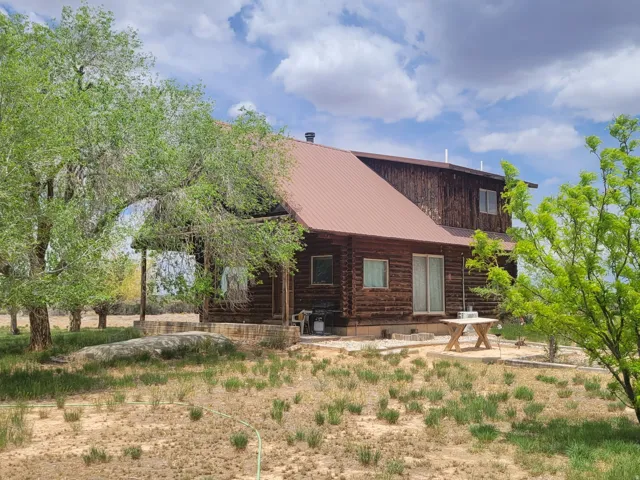 Log cabin exterior featuring a brown metal roof, wood siding, and multiple windows