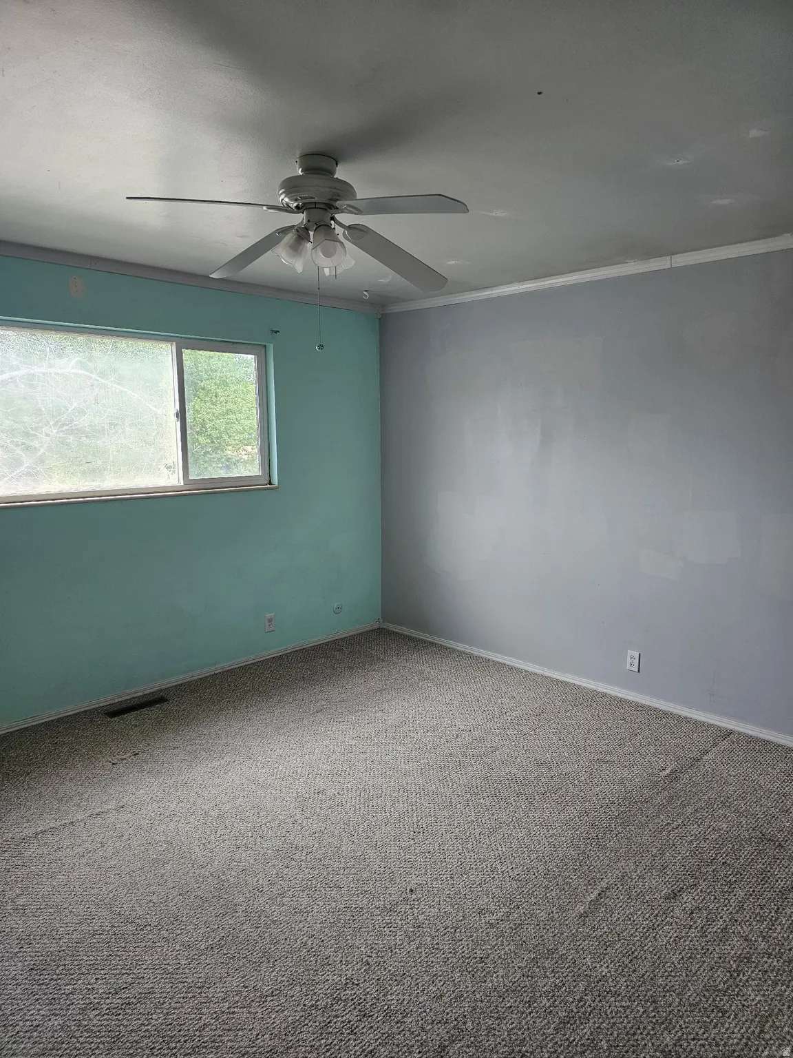 Room featuring a ceiling fan with integrated lighting, a window, baseboard trim, and wall-to-wall carpeting