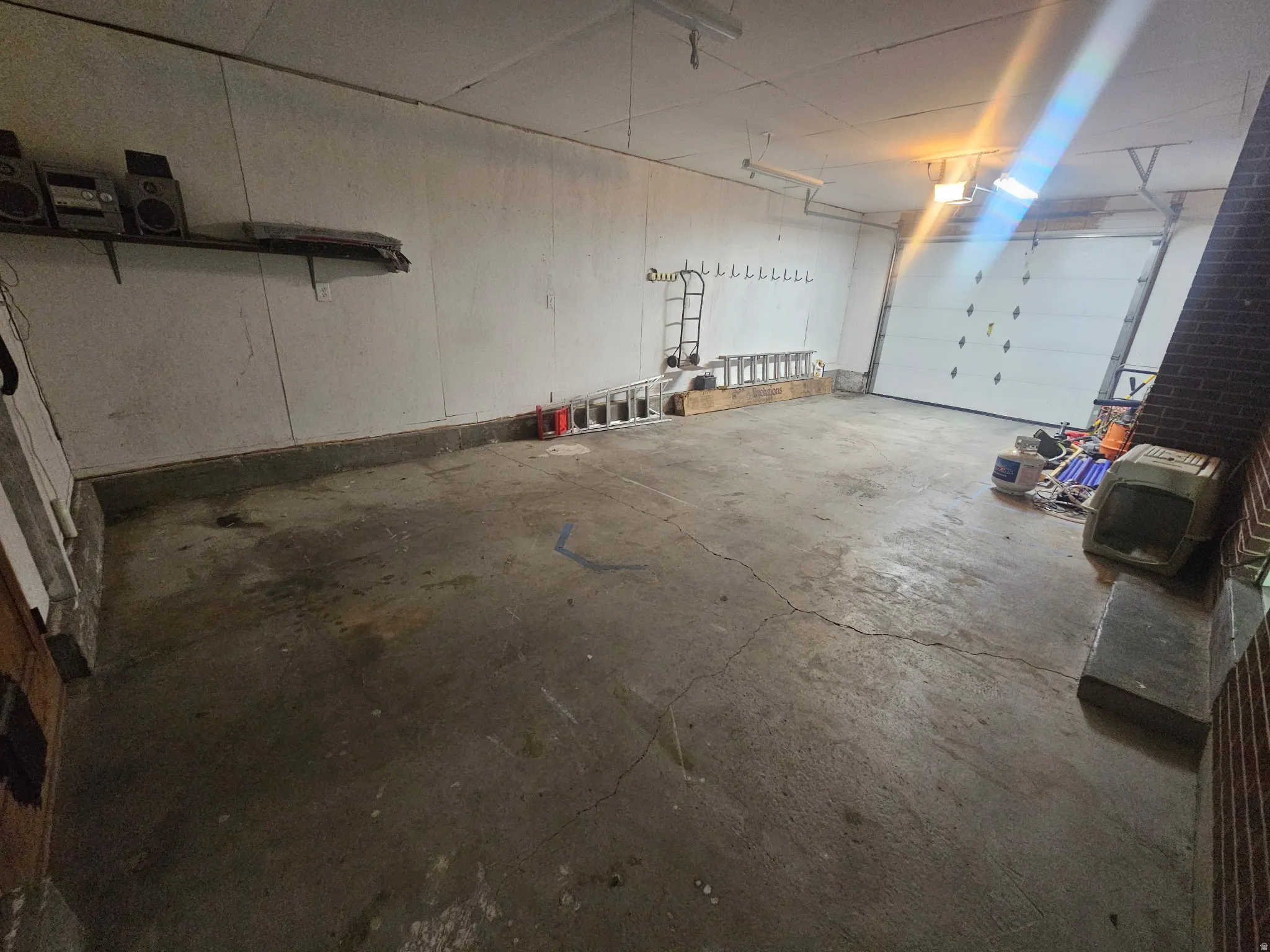 Spacious garage with a concrete floor, overhead lighting, and a roll-up garage door