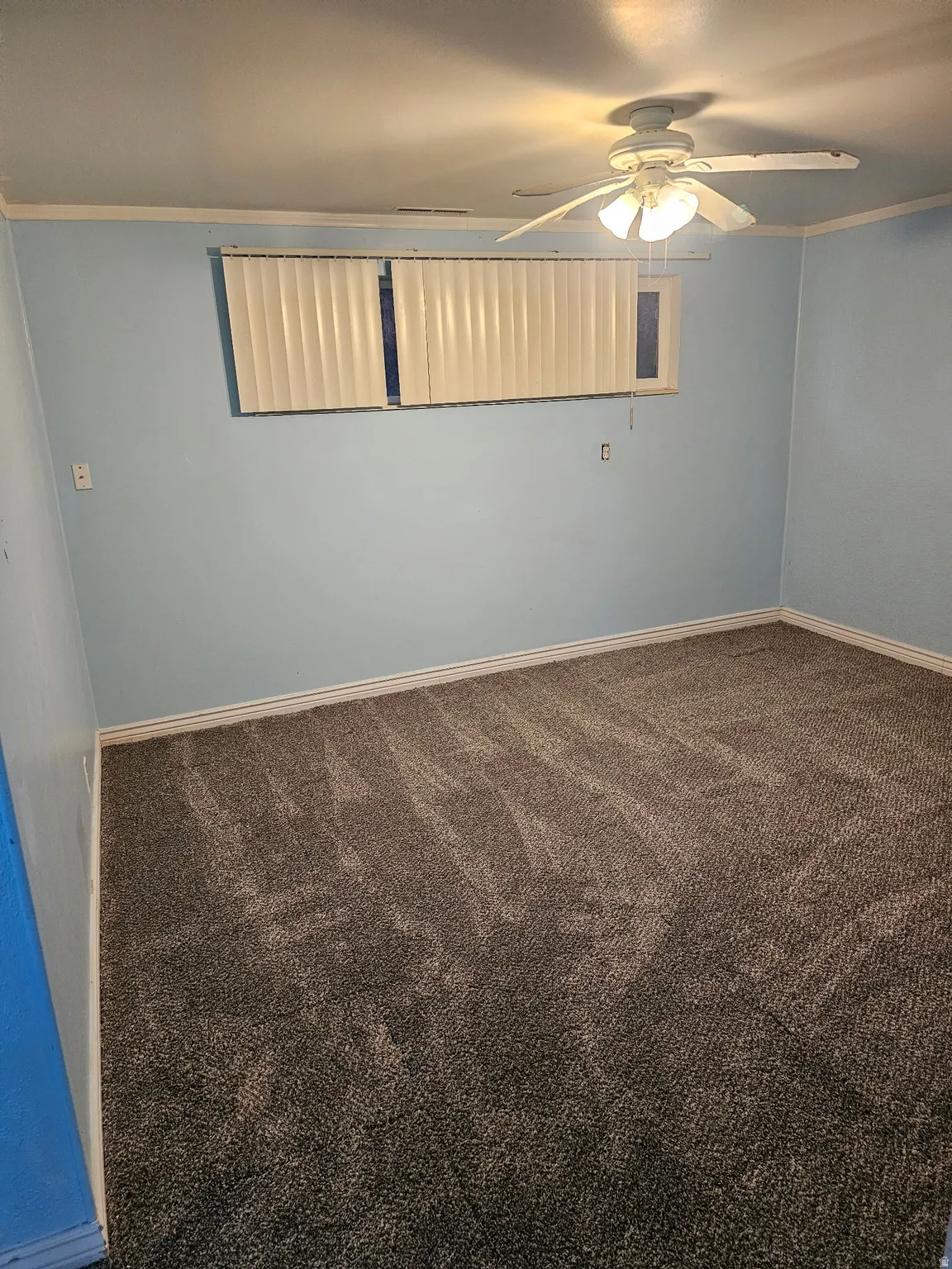 Spacious room featuring light blue walls, gray carpet, and white trim
