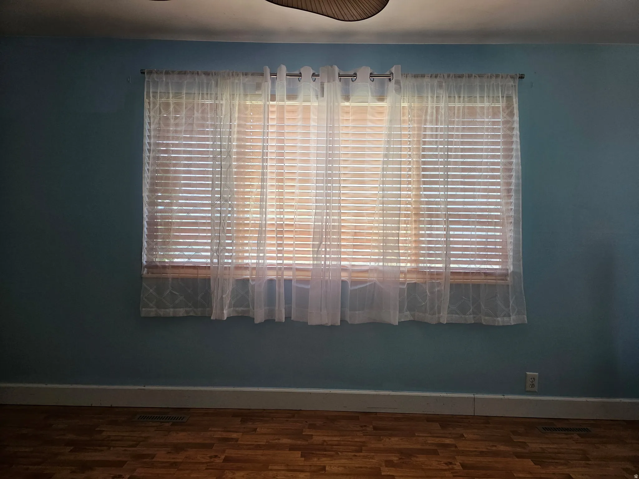 Window featuring horizontal blinds and sheer drapes