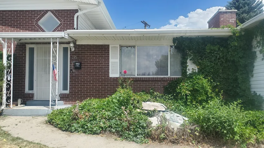 Brick facade with white trim and a covered entry featuring decorative wrought iron columns
