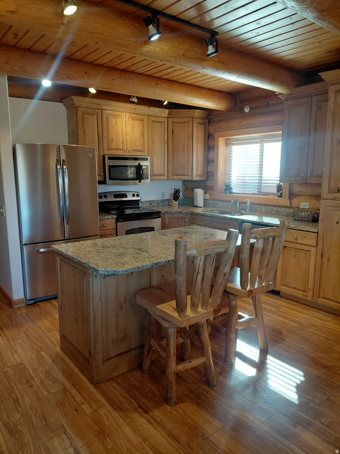 Kitchen featuring wood-finish flooring, natural wood cabinetry, and a granite island with seating