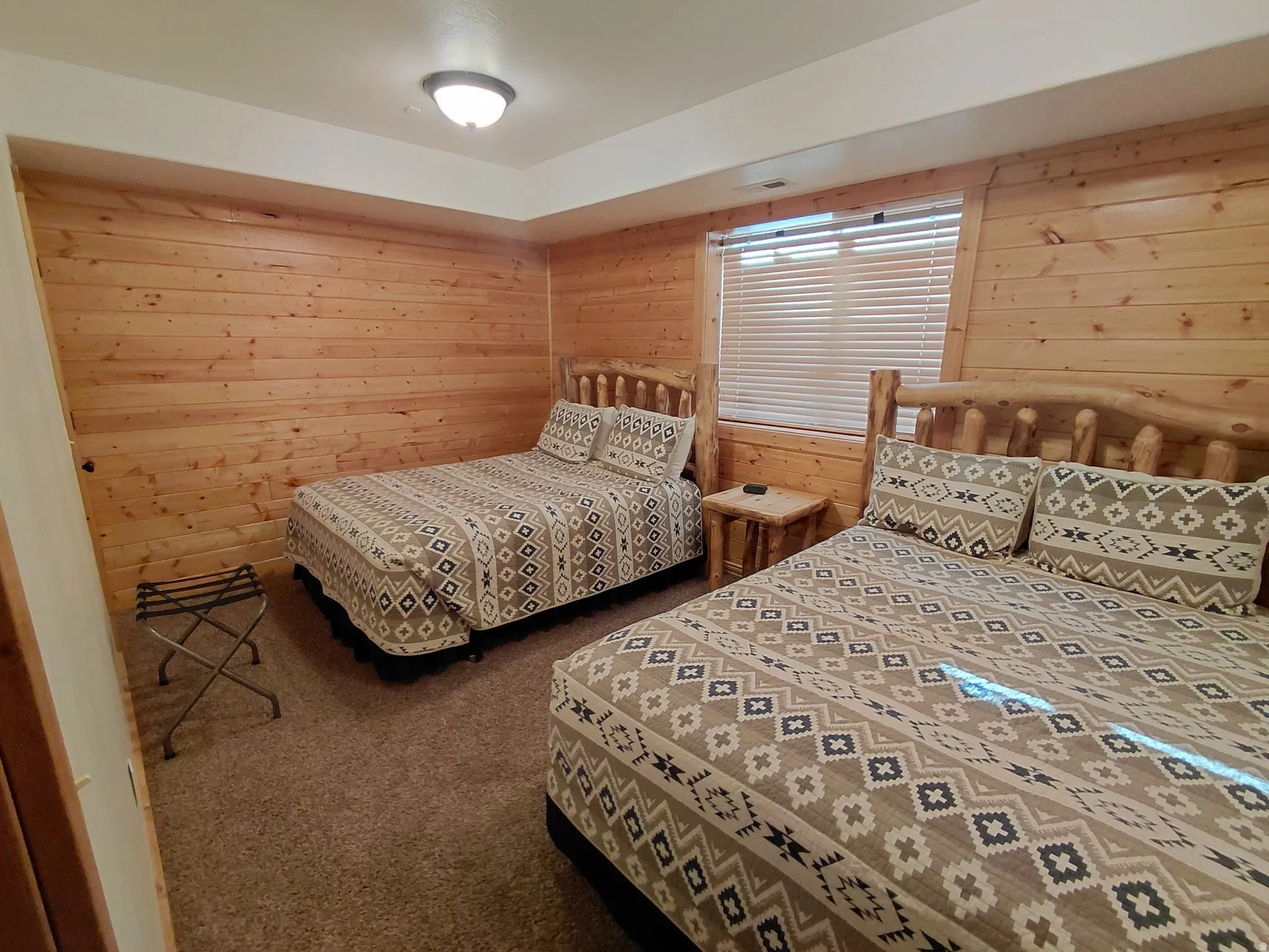 Room featuring wood-plank walls, wall-to-wall carpeting, and a flush-mount ceiling light